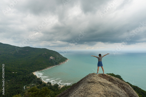 woman raising her arms on the bottle beach viewpoint , with clouds and beautiful tropical beach,koh phangan, Ko Pha-ngan, Surat Thani,thailand