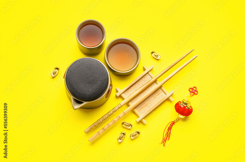 Teapot with cups, chopsticks and Chinese symbols on yellow background. New Year celebration Teapot with cups, chopsticks and Chinese symbols on yellow background. New Year celebration