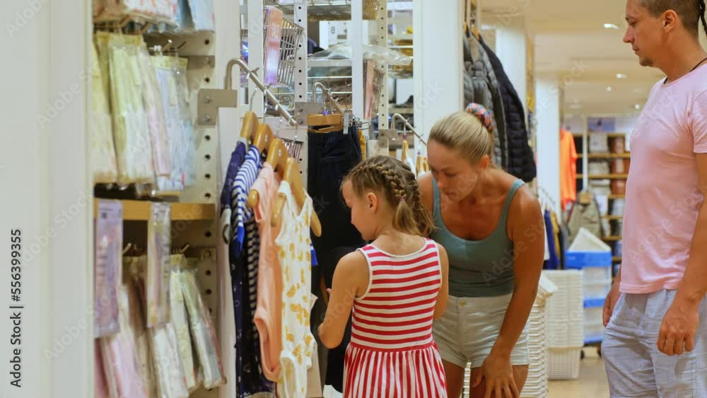 Dad and mom with her little child shopping shirt in clothing store.Happy loving family choose looking for clothes in shopping mall.Beautiful family father mother and daughter shopping in clothes shop Dad and mom with her little child shopping shirt in clothing store.Happy loving family choose looking for clothes in shopping mall.Beautiful family father mother and daughter shopping in clothes shop