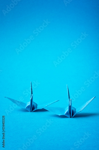 two blue origami birds on a  blue background  with copy space