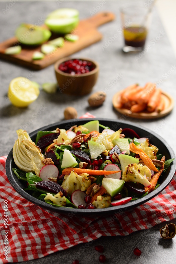Seasonal salad, healthy salad, winter vegetables, winter fruits, dark background, backlighting, beetroot, carrots, cauliflower, fennel, watercress, green apple, pomegranate. Seasonal salad, healthy salad, winter vegetables, winter fruits, dark background, backlighting, beetroot, carrots, cauliflower, fennel, watercress, green apple, pomegranate.