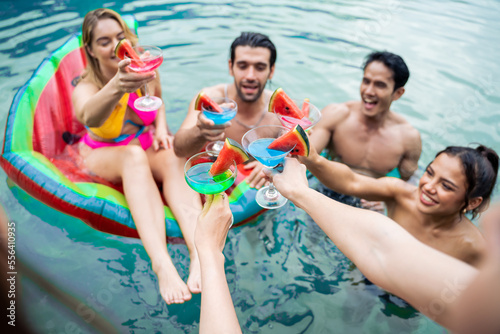 Group of diverse friend jumping into the pool, having a party together. 