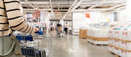 Woman with shopping cart at store, for furniture in warehouse. Many big metal shopping carts for the interior furniture on a parking lot for the customer photo