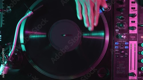 Hip hop DJ scratches vinyl record with music in overhead video clip. Club disc jockey scratching disc on turntable player on party