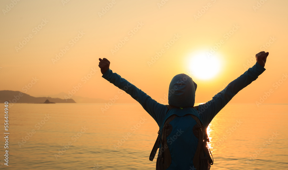 Fototapeta premium Cheering woman open arms at sunrise seaside beach