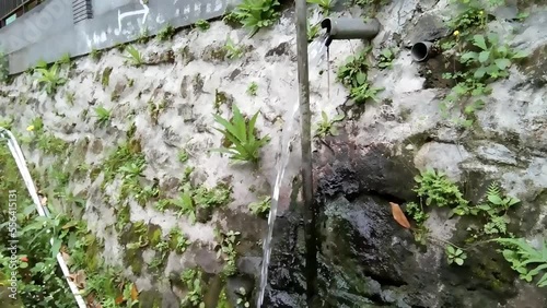 shower of water from a pipe in the wall in the mountain countryside