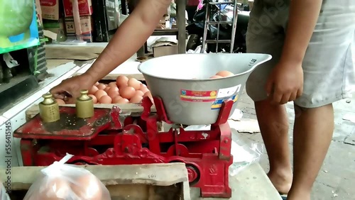 The egg seller is weighing the eggs for packing and ready for sale