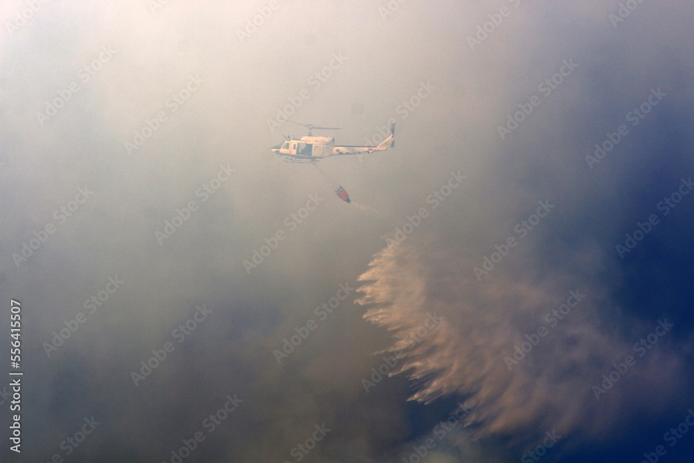 Fototapeta premium A helicopter puts out a forest fire in the mountains of northern Israel.