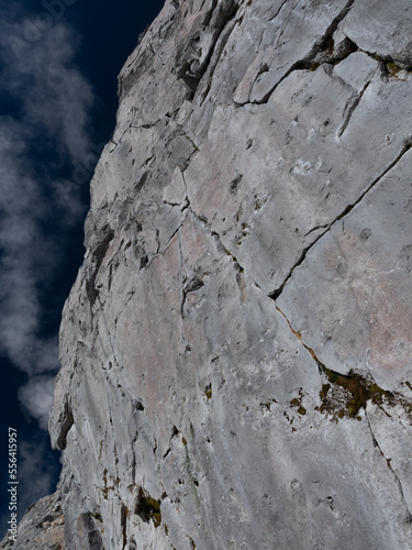 一面に真っ平な岩が垂直に聳え立つ、所々亀裂も入り重量感の岩肌、空は青くて雲が浮かんでいる。