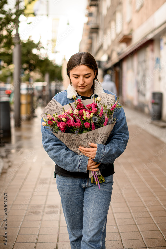Fototapeta premium handsome brunette woman with flower bouquet at street