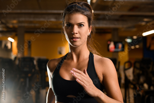 Portrait of beautiful sportive brunette woman exercising on treadmill in gym