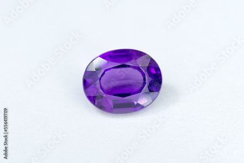 Natural deep purple color amethyst loose gemstone mined in Uruguay. Oval cut, poor quality cutting and bad polishing, finish. Scrathes on stone facet surface. White background. Gemology, mineralogy. 
