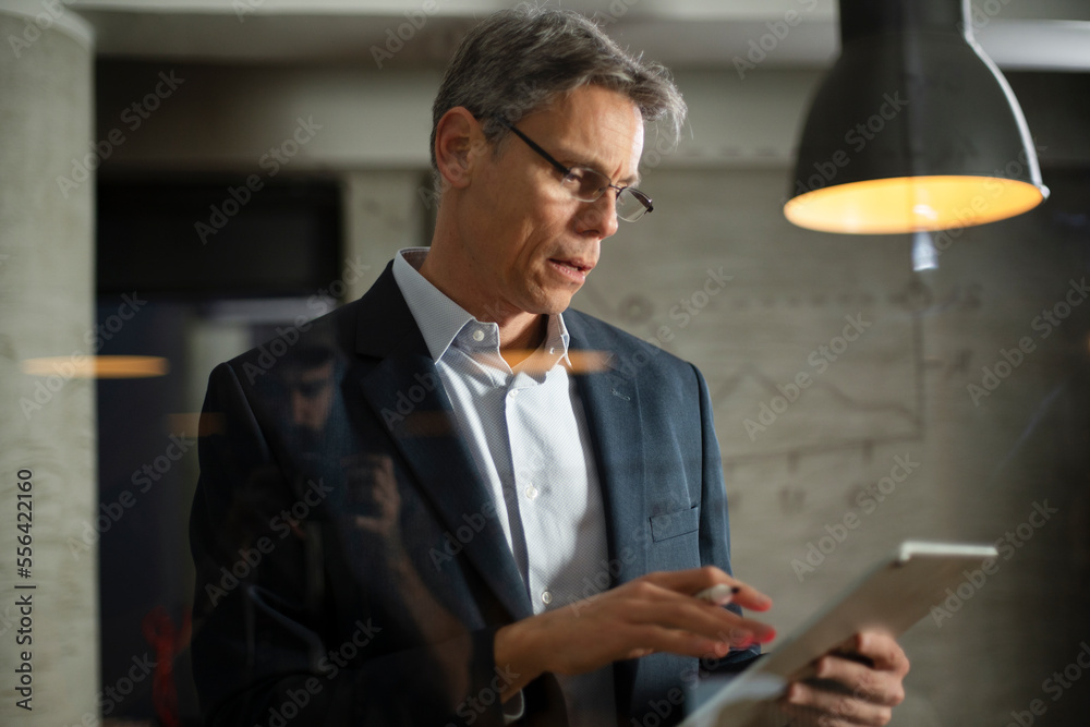 Portrait of successful businessman in office. Man writing on the glass board in office.. Portrait of successful businessman in office. Man writing on the glass board in office..