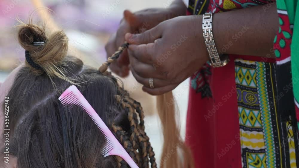 Video „Traditional African woman doing braids to a tourist girl in her