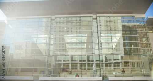 Exterior of large aesthetic glass building with sun flares and reflections, smooth downward motion to reveal.