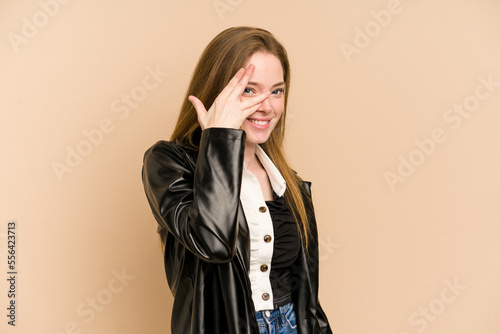 Young redhead woman cut out isolated blink at the camera through fingers, embarrassed covering face. © Asier