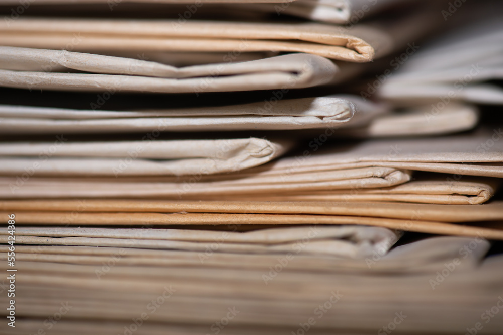 Gros plan sur une pile de vieux journaux. Le bord de certains exemplaires est jauni, la netteté est réalisée sur une petite zone pour voir la texture du papier Gros plan sur une pile de vieux journaux. Le bord de certains exemplaires est jauni, la netteté est réalisée sur une petite zone pour voir la texture du papier