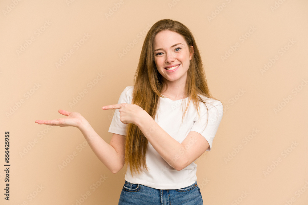 Young redhead woman cut out isolated excited holding a copy space on palm. Young redhead woman cut out isolated excited holding a copy space on palm.