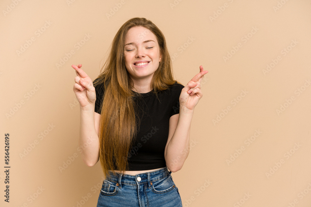 Young redhead woman cut out isolated crossing fingers for having luck Young redhead woman cut out isolated crossing fingers for having luck