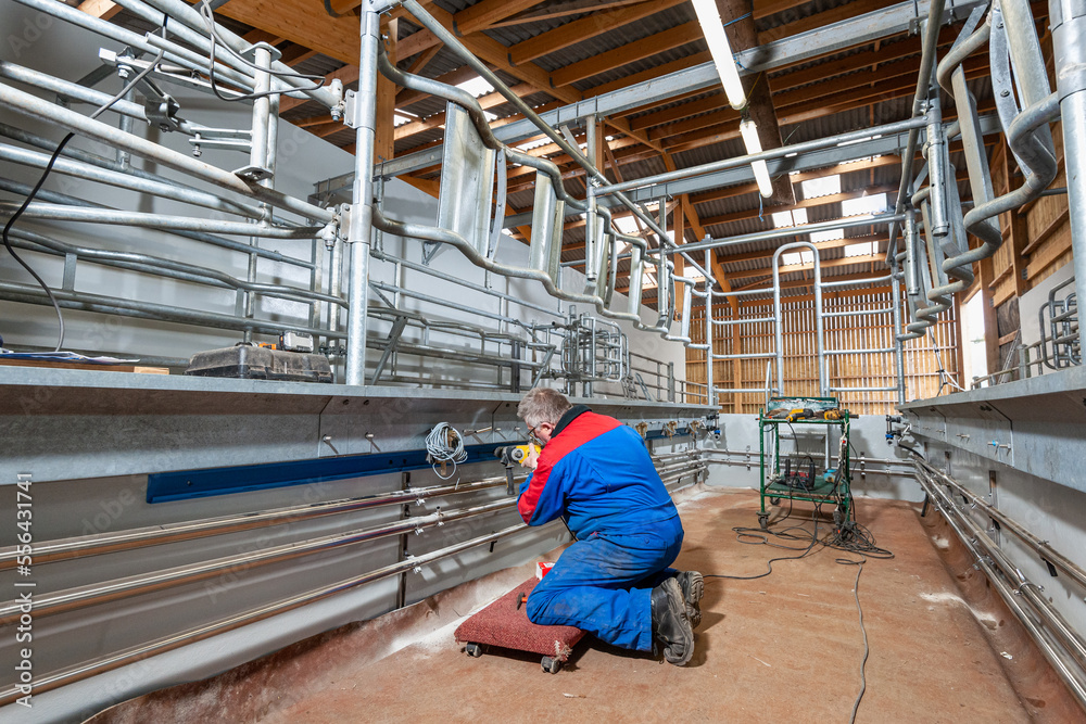 Installation d'une salle de traite neuve 2 x 6 postes par une entreprise spécialisée. Discussion devant un plan entre l'agriculteur et le technicien