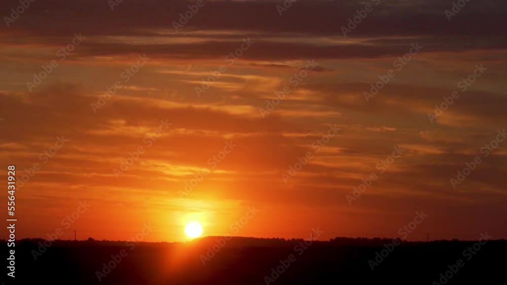 Beautiful Bright Orange Sky with Clouds at Sunset Time Lapse. The Sun Sets Over The Horizon In A Field At Sunset. Beautiful Bright Orange Sky with Clouds at Sunset Time Lapse. The Sun Sets Over The Horizon In A Field At Sunset.