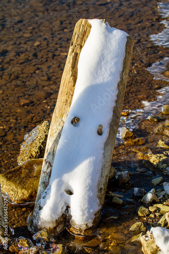 Tête spontanée du bonhomme de neige se dessinant sur un poteau couvert de neige fondant au soleil; Oeuvre d'art naturelle photo