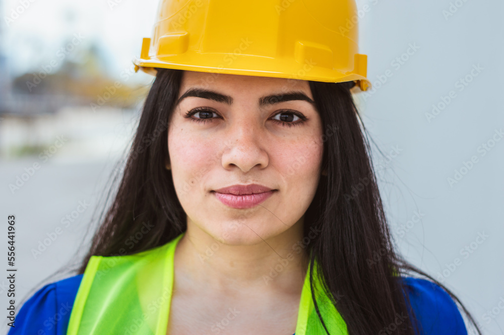portrait of young latin woman engineer, cool and calm, standing on the street, looking at the camera