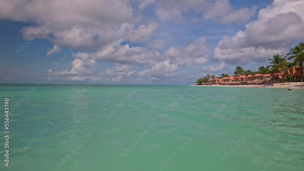 Gorgeous view of hotel buildings on front of sandy coastline of Atlantic Ocean. Turquoise water merging with blue sky on horizon. Aruba Island. Gorgeous view of hotel buildings on front of sandy coastline of Atlantic Ocean. Turquoise water merging with blue sky on horizon. Aruba Island.