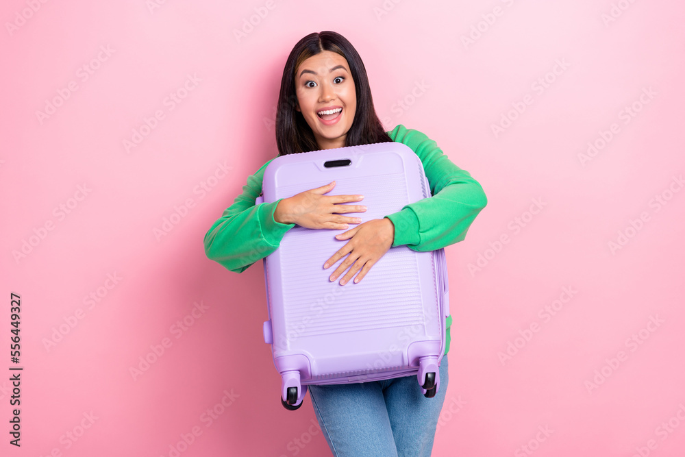 Photo of impressed excited girl dressed green sweatshirt rising holding baggage isolated pink color background Photo of impressed excited girl dressed green sweatshirt rising holding baggage isolated pink color background