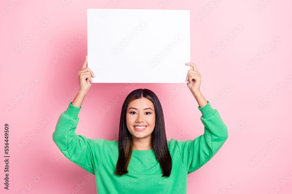 Photo of cute sweet girl dressed green sweatshirt holding white billboard empty space isolated pink color background Photo of cute sweet girl dressed green sweatshirt holding white billboard empty space isolated pink color background