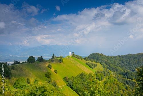 Mountain scenery with church on the mountain ridge. Colorful sunset scenery and cute Saint Primoz church with high mountains in background, Jamnik village, Slovenia, Europe