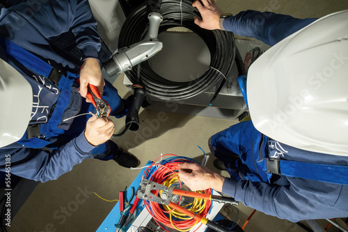 Engineers try to put cables in plug to charge electric car. Foremen use pliers and install cables in adapter for electric cars on stations