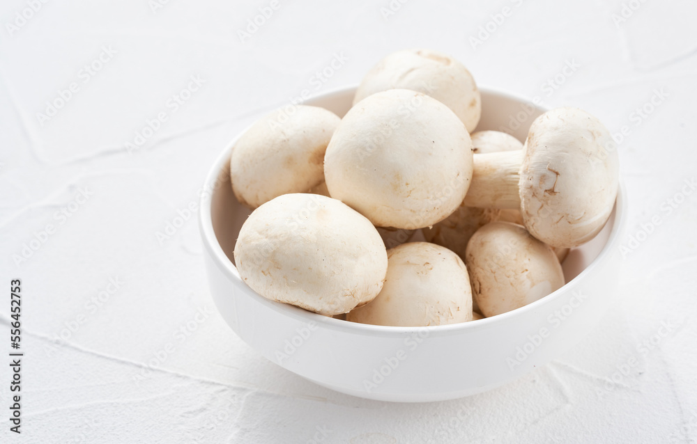 white champignon button mushroom in bowl on white table background. pile of white champignon button mushroom. group of champignon button mushroom