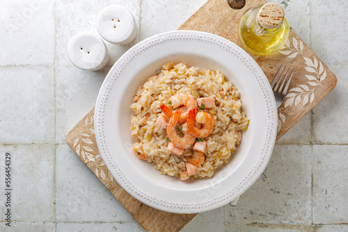 Top view of risotto with prawns, salmon, leek and tangerine. Rice dish.