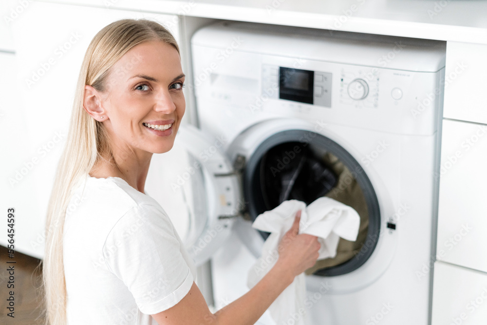 happy female housewife load laundry in washer appliance at home happy female housewife load laundry in washer appliance at home