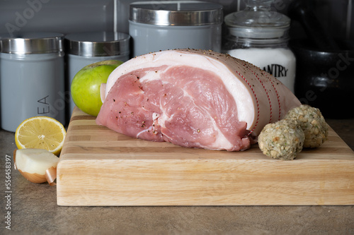 uncooked Leg of Pork joint on a beech block cutting board with onion, lemon  cooking apple and sage and onion stuffing balls photo