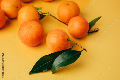 Orange mandarins clementine with green leaves on a yellow background. Front view