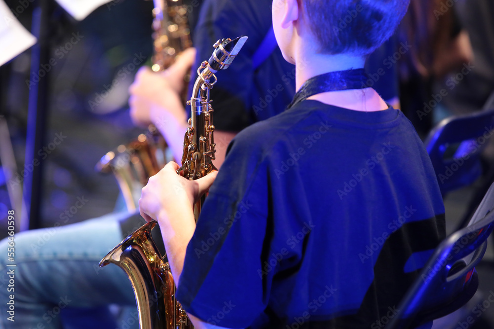 Φωτογραφία Portrait of a teenage boy holding a saxophone sitting in an orchestra close-up r