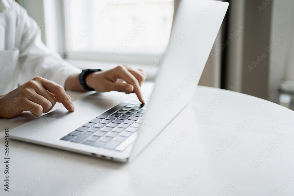 A woman uses a computer on a table. Prints text on the laptop keyboard. A person works online on the Internet, a workplace. A woman uses a computer on a table. Prints text on the laptop keyboard. A person works online on the Internet, a workplace.