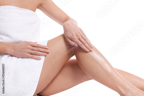 Woman applying body cream onto her leg against white background  closeup