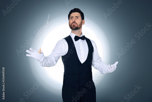 Professional conductor with baton on grey background