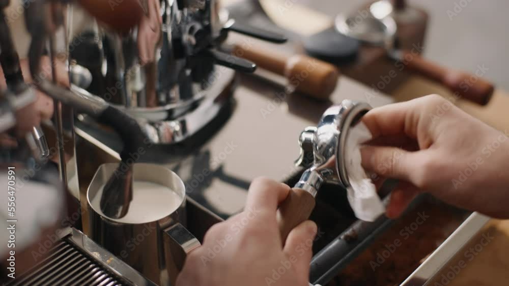 Close-up handheld shot barista works in cafe, male hands cleaning horn holder portafilter, process of making espresso coffee Close-up handheld shot barista works in cafe, male hands cleaning horn holder portafilter, process of making espresso coffee