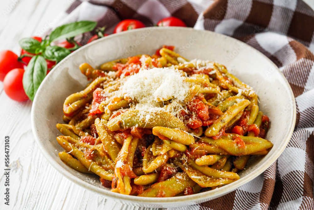 green cavatelli pasta with spinach in tomato sauce on a white wooden background green cavatelli pasta with spinach in tomato sauce on a white wooden background