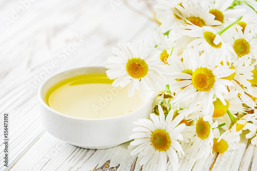 aromatic chamomile essential oil on a white wooden rustic background