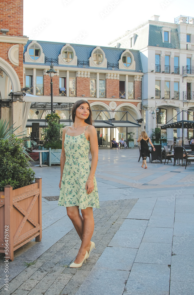Nice brunette young woman wearing yellow dress walking in city. Nice brunette young woman wearing yellow dress walking in city.