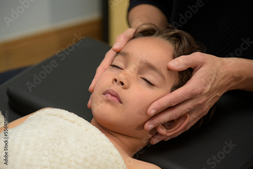 Caucasian woman practicing osteopathy on a child