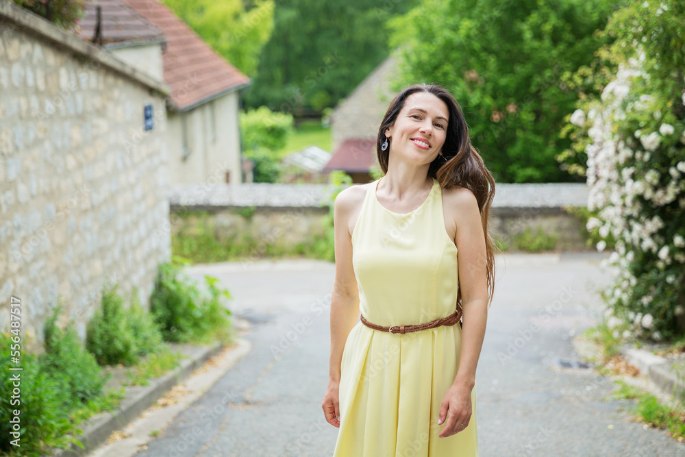 Lifestyle portrait of young stylish woman with long brunette hair walking on the street in old town, wearing yellow dress Lifestyle portrait of young stylish woman with long brunette hair walking on the street in old town, wearing yellow dress