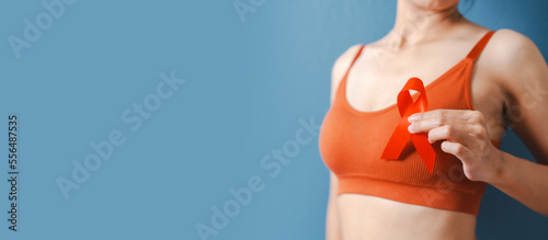 Medicine charity support concept. Close up asian woman in orange bra hands holding ribbon for cancer sign concept.