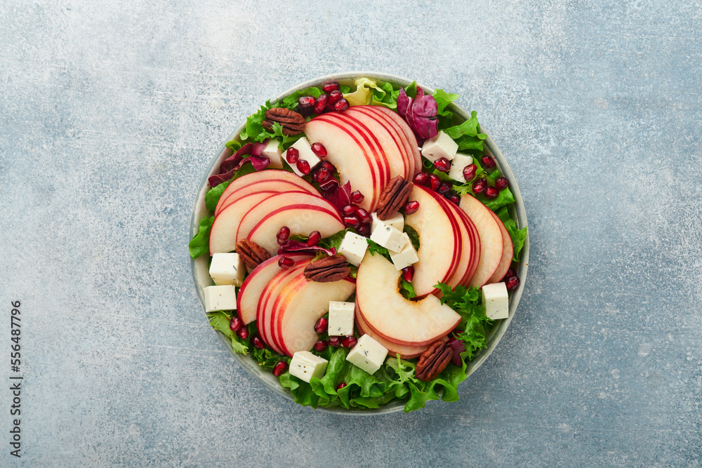 Salad. Fresh fruit green salad with feta cheese, apple, pomegranate, pecan and lettuce on white plate. Idea for healthy delicious winter Christmas salad. Healthy balanced eating. Top view.