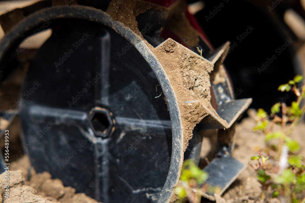 Black metal cultivator wheel. The farmer will plow the land preparing the soil for sowing. Selective focus